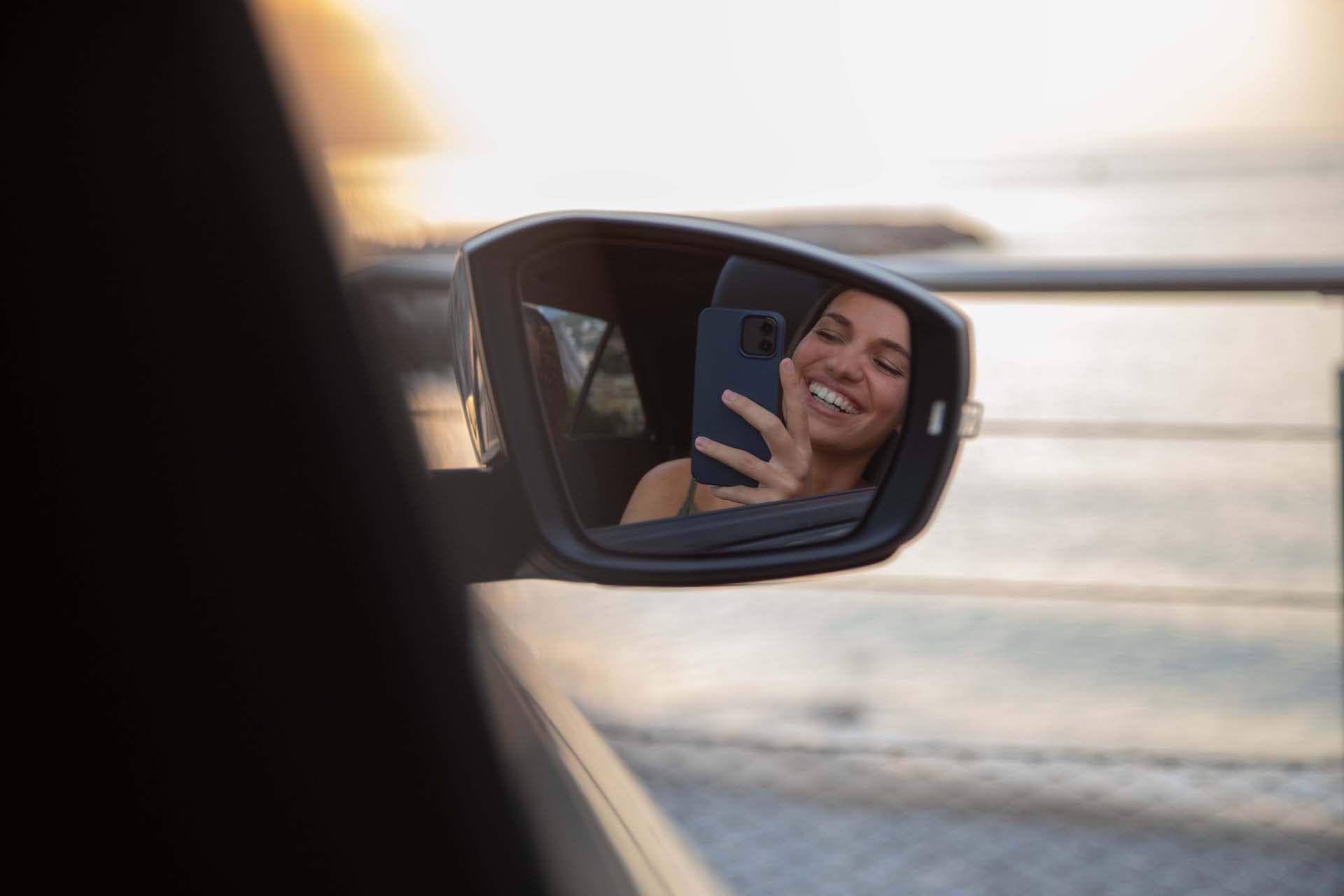 Femme qui se prend en selfie dans le rétroviseur d'une voiture